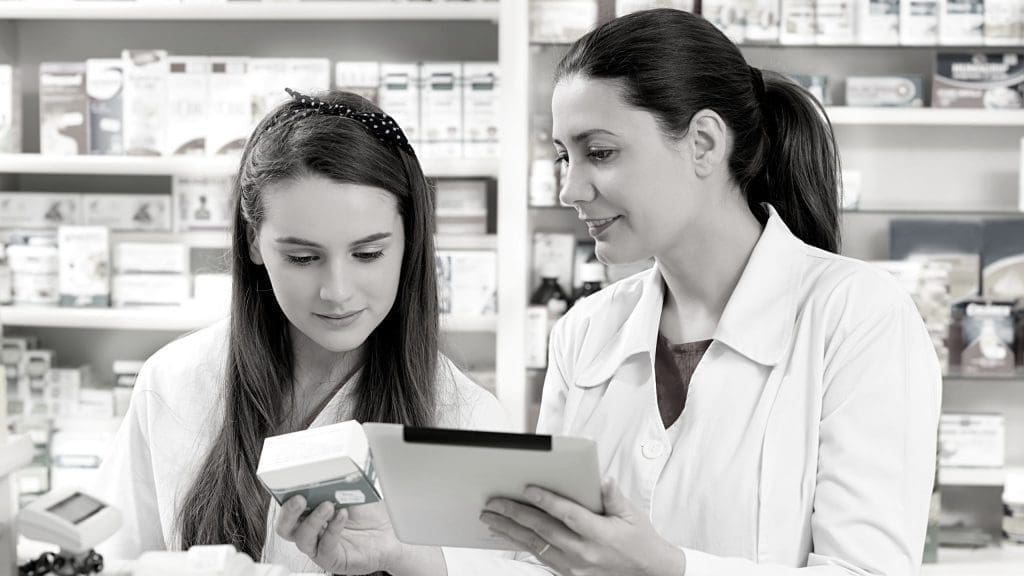 two pharmacists check inventory records to ensure they are CSA-compliant.