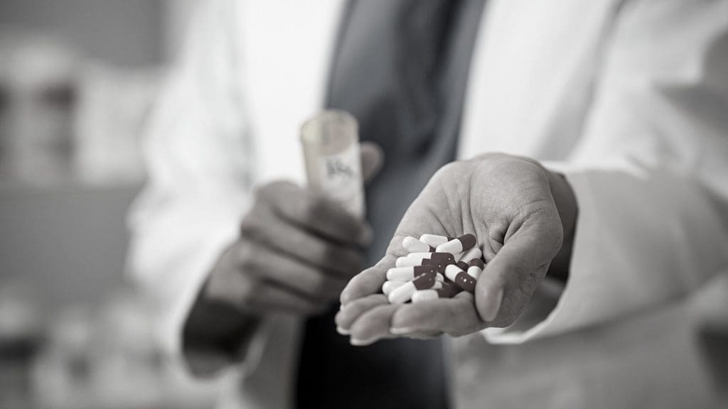 Close-up of pharmacist's hand holding pills.