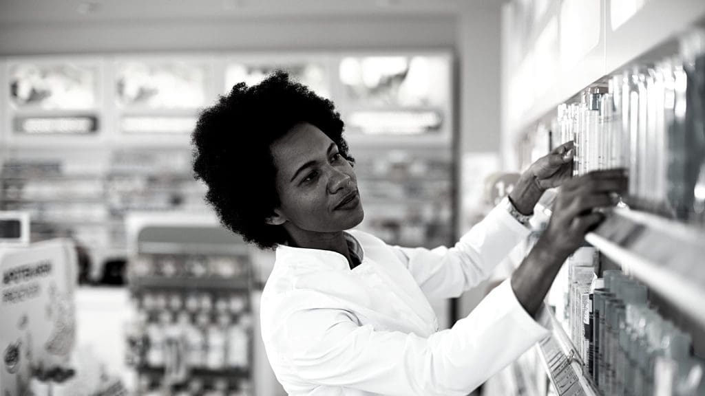 a female pharmacists arranging drugs on a shelf in a pharmacy
