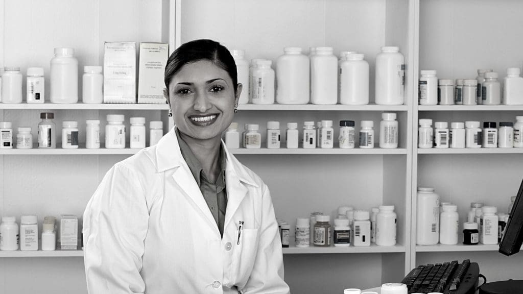 a female pharmacists smiling next to a computer