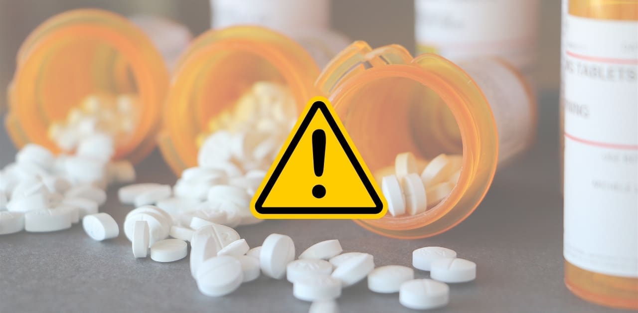 A warning sign with a faded image of prescription bottles in the background used to visualize that the Controlled Substance Monitoring Program (CSMP) gives wholesalers the power to set thresholds on the prescriptions pharmacies can purchase.